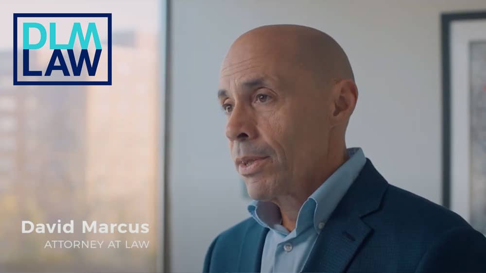 A man in a suit stands indoors, looking to the side. The text on the image reads "David Marcus, Attorney at Law" with a "DLM Law" logo in the corner.