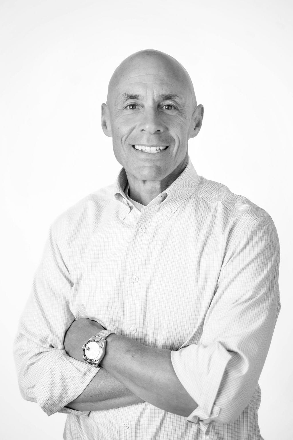 david marcus casual-min David Marcus of DLM law wearing a light-colored, long-sleeve button-up shirt stands with arms crossed and smiles at the camera against a plain white background.
