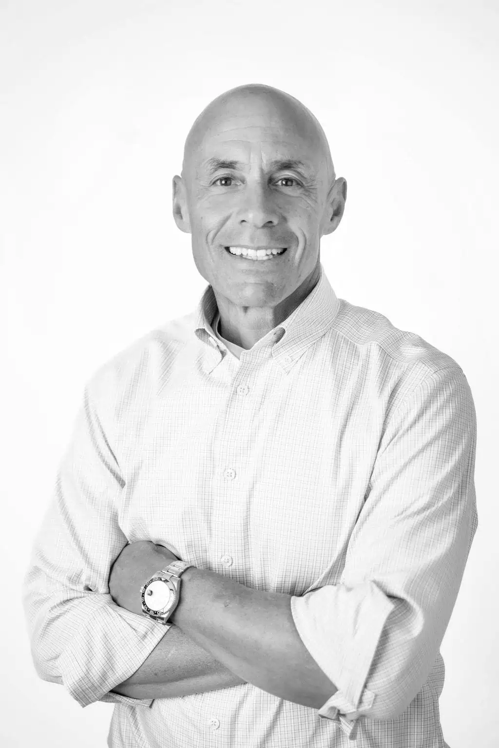 david marcus casual-min David Marcus of DLM law wearing a light-colored, long-sleeve button-up shirt stands with arms crossed and smiles at the camera against a plain white background.
