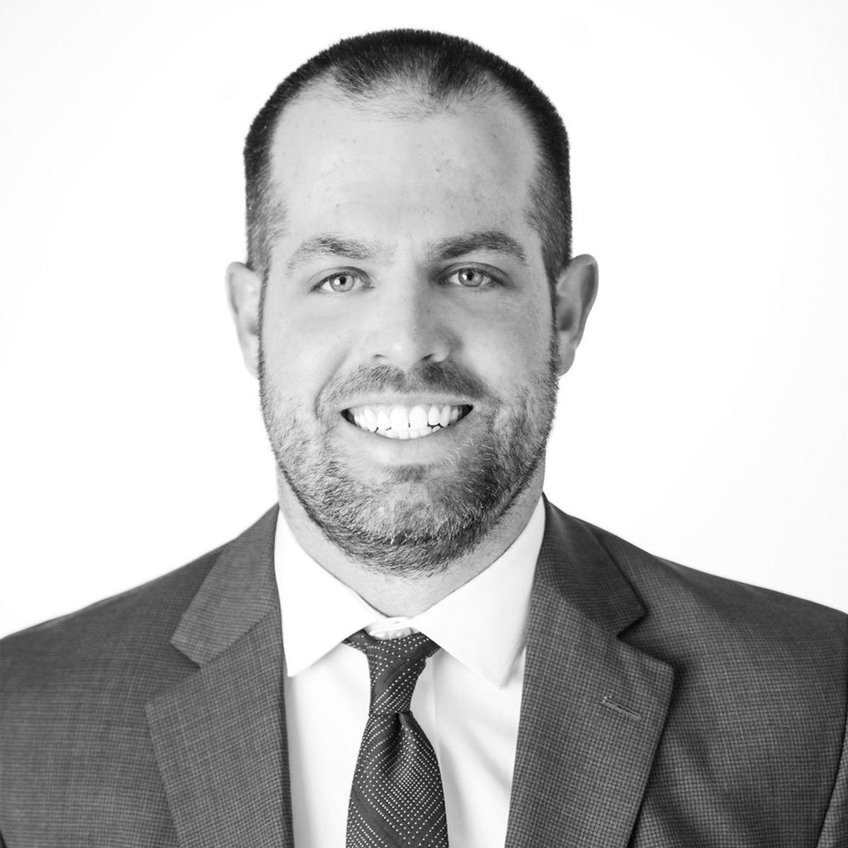 resized-ben-donovan Ben Donovan in a suit and tie smiles at the camera in a black-and-white portrait with a plain white background.